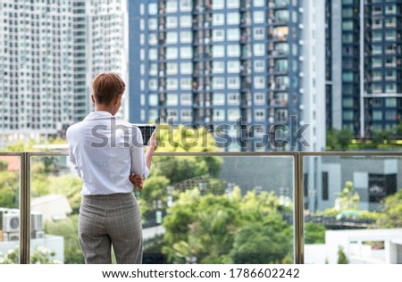 Back view of business woman looking at the city and holding tablet stock photo