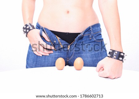 waist detail of woman wearing black underwear and blue jeans in front of two brown eggs