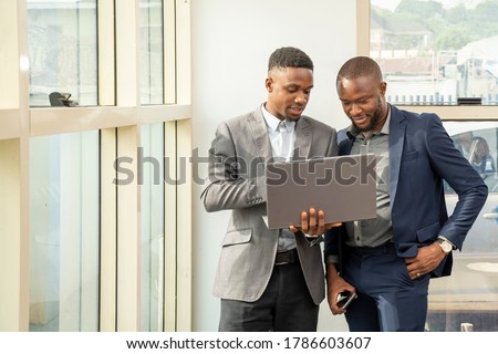 young black business men standing together holding a laptop, discussing business Royalty-Free Stock Photo #1786603607