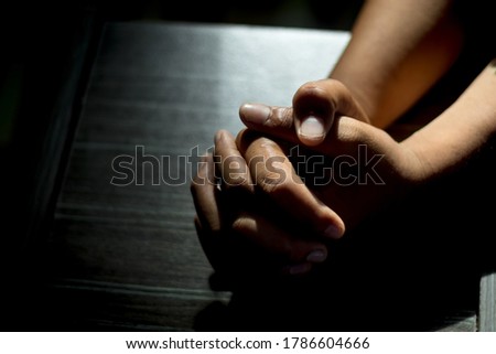 An Asian man is praying for a blessing from God, as the sunlight shines through the palm.  In the empty space at the left to insert text Or use the pictures to compose religious publications 