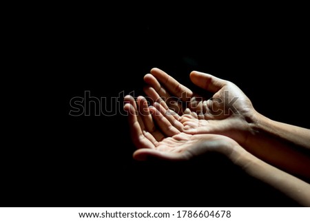 An Asian man is praying for a blessing from God, as the sunlight shines through the palm.  In the empty space at the left to insert text Or use the pictures to compose religious publications 