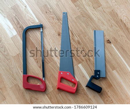 The set of construction tools includes different saws on wooden background for use in manufacturing process industrial sector. Home repair their own hands.