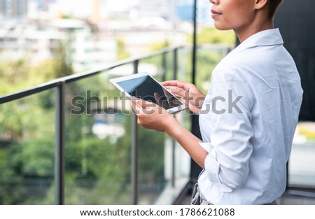 Unrecognizable business woman looking at the city and holding tablet stock photo