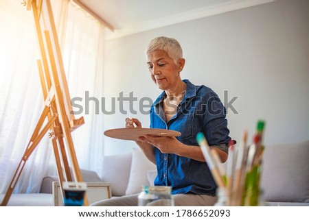 Senior artist woman drawing at home. Senior female artist working on a painting. Senior woman artist enjoying her hobby at home. Creative mature woman Royalty-Free Stock Photo #1786652093