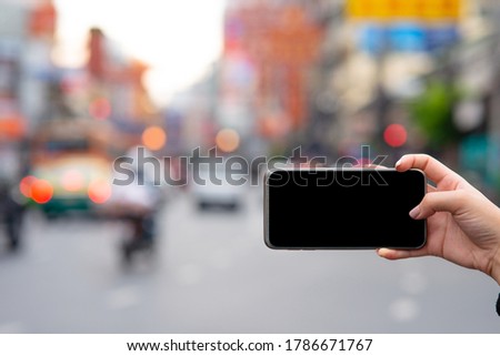 Black screen smart phone of girl taking a picture near chinese market while her travel in the city