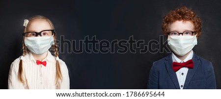 Child girl and boy in protective medical mask on blackboard background with copy space