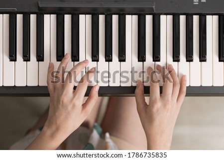 Top view of young woman playing piano.  