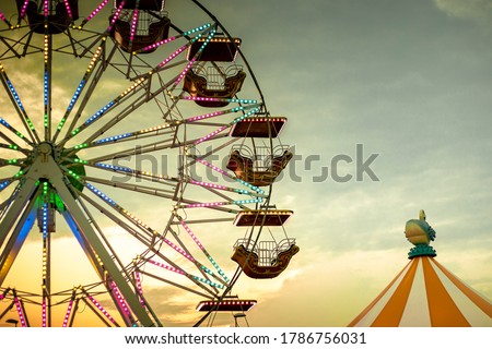 Colorful ferris wheel at sunset, illuminated by neon lights with a circus tent. Background with copy space. Rosolina Mare amusement park, Veneto, Italy. Royalty-Free Stock Photo #1786756031