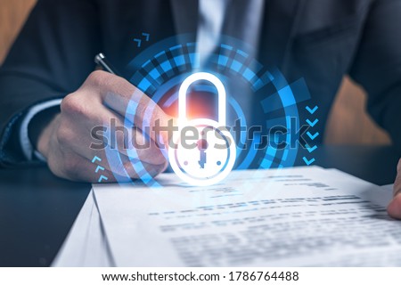 Businessman in suit signs contract. Double exposure with lock icon hologram. Man signing agreement on company data security. Safety concept.