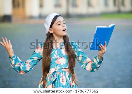 Girl student reading book outdoors, recite poetry concept. Royalty-Free Stock Photo #1786777562