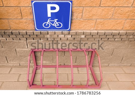 Bicycle parking and road sign. View from the front. In the city near the house. Metallic design