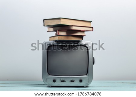 Retro tv receiver with stack of books on white background