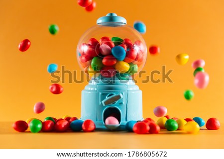 front view of a handful of gummy sweets with a candy machine dispenser, colors red, yellow, green, blue and pink. Royalty-Free Stock Photo #1786805672