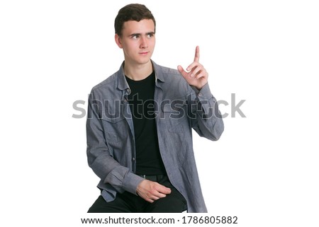 A young man in a Manatee shirt, black t-shirt and trousers, isolated on white, points up at copyspace