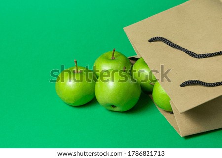 Green apples on a green background. Apples fell out of a paper bag.