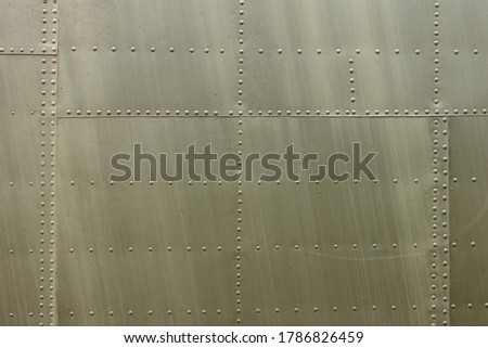 Details of the fuselage of an old aircraft. Old camouflage surface with exfoliated paint and rivets on a military aircraft. Royalty-Free Stock Photo #1786826459