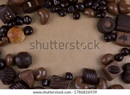 Chocolate pralines frame top view stock images. Chocolate candies on a brown background. Chocolate frame top view. Chocolate pralines background with copy space for text. Border of different pralines
