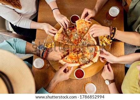 High angle view of group of friends having pizza for lunch in a pub. 