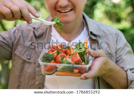 Close-up of a young man eating a fresh vegetable salad, shallow depth of field, selective focus. Healthy food concept