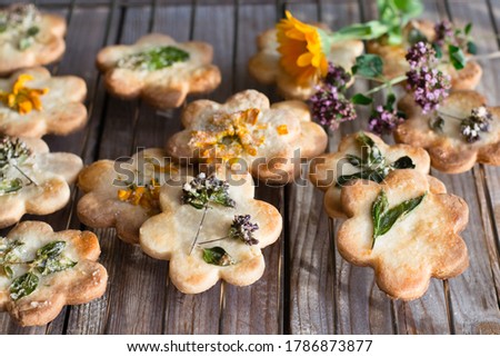 Edible flowers cookies on plate, on wooden table