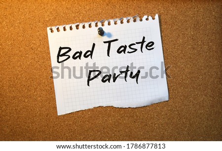 Paper note written with BAD TASTE PARTY inscription on cork board