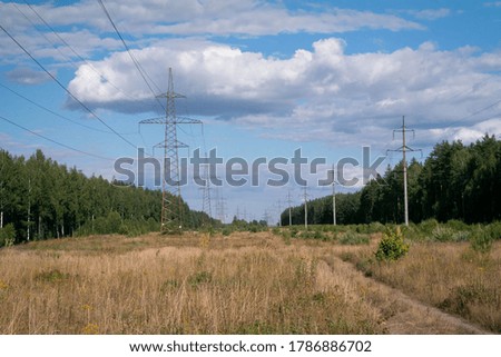 Lots of high-voltage towers and wires running between the woods, forest. Delivery of electricity to localities and cities.