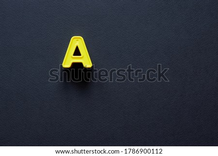 Yellow letter A uppercase. Capital letter A isolated on black background; copy space, top view