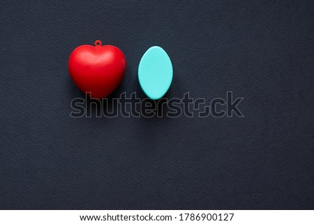 Red heart and blue oval ellipsoid isolated on black background; copy space, top view