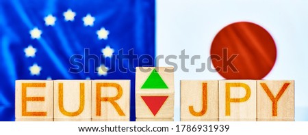 eur jpy. wooden blocks with the inscription eur jpy with arrows symbolizing the rise and fall of the currency pair against the background of national flags