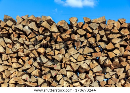 Logs of wood  piled together in lumber-mill with blue sky in the top of the picture