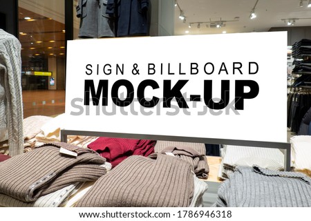 Mock up horizontal signboard with clipping path at shelf show winter cloths, blank space for insert advertising or information indoor billboard in clothing store