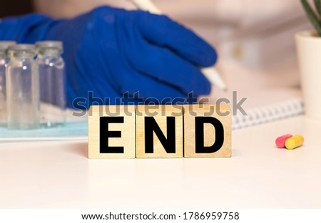 The end word sign with wooden blocks on a table with hands in medical gloves