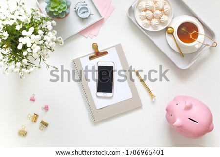 White and gold stationery at the female workplace. Jewelry, bracelets and rings. Alarm clock and pig piggy bank. Scandinavian nordic style. Stylized women's desk, office desk. Royalty-Free Stock Photo #1786965401