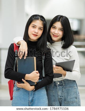 Portrait of female teenager college student holding books with school backpack and wearing graduation hat represent graduation concept. Education stock photo.