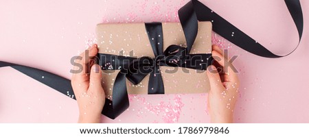Merry Christmas present stylish gift box in kids hands on pink background. Creative Flat layout top view composition, banner, xmas, new year, mother day, black friday concept
