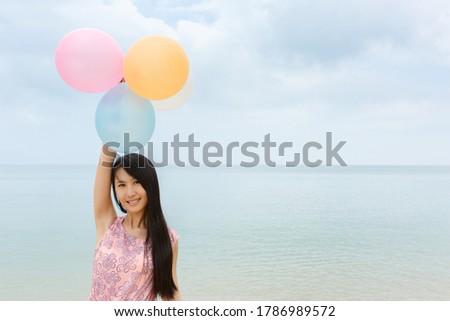 Pretty young girl   holding balloon at seaside