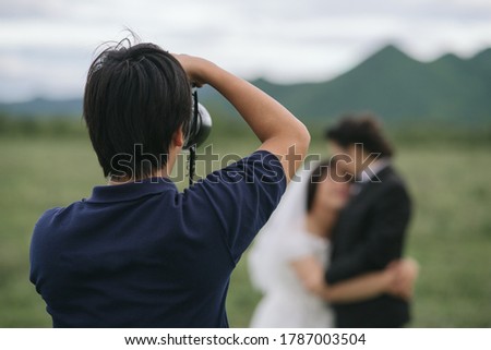 wedding photographer in action, wedding photographer takes pictures of the bride and groom in nature. Behind the scene of photogrphy working concept.