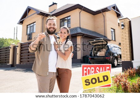 Portrait of excited young couple have bought house and showing key to camera, moving into new house concept