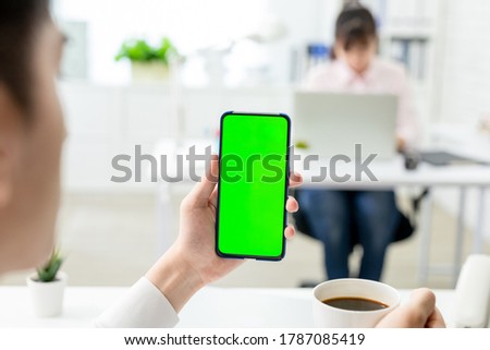 asian young businessman look to green screen smart phone in the office