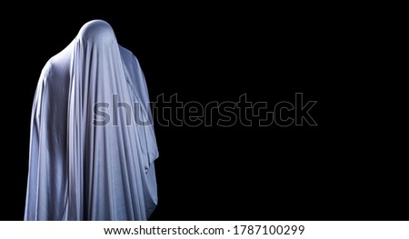 The man is in white clothes and shows a scary looking face on isolated black background, look like ghost in night for Halloween Festival concept, Copy space