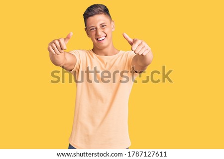 Young handsome man wearing casual clothes approving doing positive gesture with hand, thumbs up smiling and happy for success. winner gesture. 
