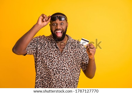 Photo of crazy funny dark skin guy hold wireless plastic credit card cool nice offer online shopping wear sun glasses golden necklace leopard shirt isolated bright yellow background