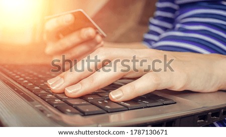 Close-up of a woman's hands holding a credit card and using a laptop. concept of online shopping