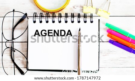 AGENDA written in a notebook on white background with office tools