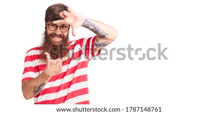 Handsome young red head man with long beard wearing casual clothes smiling making frame with hands and fingers with happy face. creativity and photography concept. 