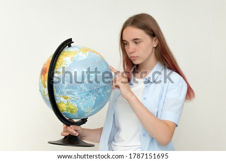 A high school student holds a globe in her hands and carefully examines it. Geography. World. Earth. Thoughtful girl. Looking for a place to travel -Horizontal photo