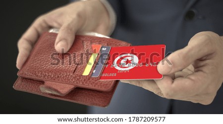 Man pulls plastic bank card with flag of Tunisia out of his wallet, fictional card number