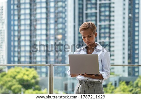 Business woman using laptop computer outdoor with office building in the background stock photo