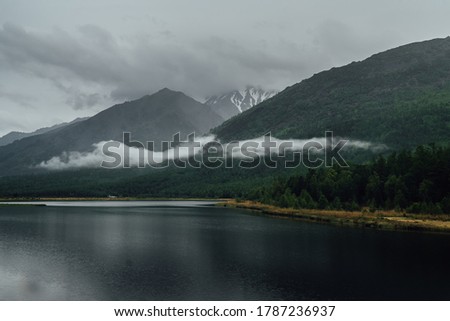 the western shore of baikal in rainy weather with clouds on the mountains