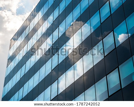 Modern skyscraper in business district with the sky reflecting in the glass windows.